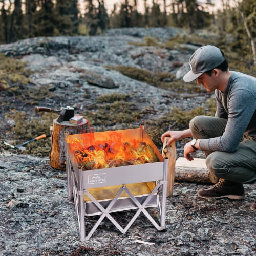 A guy using a portable camping fire pit