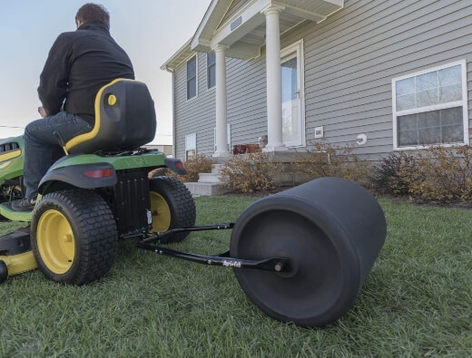 A man using a tow behind lawn roller