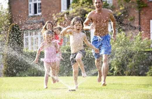 A family playing with their garden sprinkler
