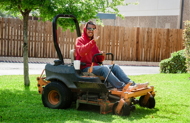 A man mowing the lawn using a zero turn mower